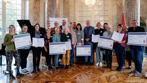 Sozial- und Integrationsminister Klose ehrt die Preisträger des Wettbewerbs "Aktion Generation – lokale Familien stärken" im Schloss Biebrich Sozialminister Klose mit einer Gruppe von Preisträgerinnen und Preisträgern. Sie halten Gewinnschecks in den Händen und sind zum Gruppenbild aufgestellt.