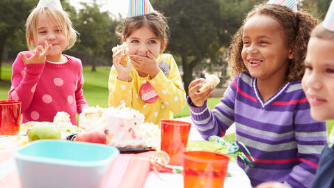 Lachende Kinder am Tisch feiern einen Geburtstag 