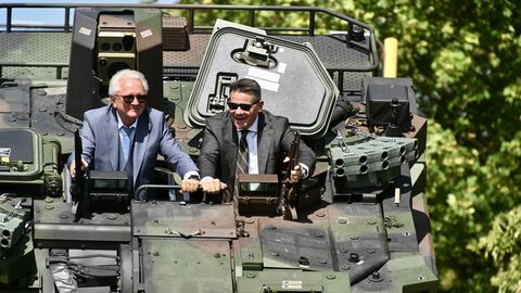 Zwei Personen sitzen in einem Panzerfahrzeug. 