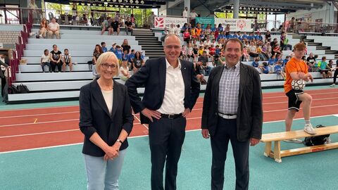 Kultusminister Lorz und Sportminister Beuth besuchen inklusive Bundesjugendspiele in Frankfurt-Kalbach Martina Schneider, kooptiertes Präsidiumsmitglied Special Olympics Hessen, Innen- und Sportminister Peter Beuth und Kultusminister Prof. Dr. R. Alexander Lorz stehen auf einer Tartanbahn ihn einem Sportstadion. Im Hintergrund Kinder in Sportkleidung.