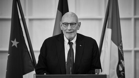 Claus Friedrich Wisser am Rednerpult, im Hintergrund Flaggen.