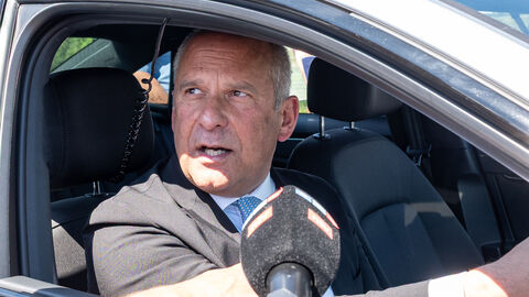 Innenminister Roman Poseck sitzt in einem Zivil-Fahrzeug mit Blaulicht und spricht in ein Mikrofon.