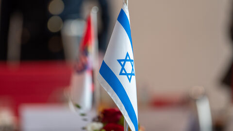 Israelische Flagge die durch eine starke Tiefenschärfe im Vordergrund steht. Im Hintergrund sieht man unscharf die hessische Flagge.